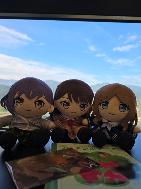 青空と山を背景に並ぶ三体のぬいぐるみ